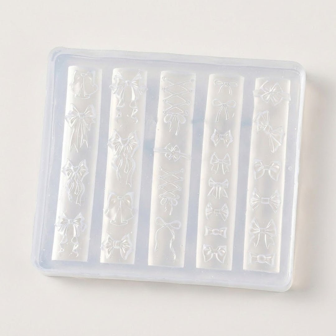 A translucent silicone mold tray with five vertical slots, each featuring embossed bow and ribbon patterns, shown on a plain off-white background.