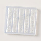 A translucent silicone mold tray with five vertical slots, each featuring embossed bow and ribbon patterns, shown on a plain off-white background.
