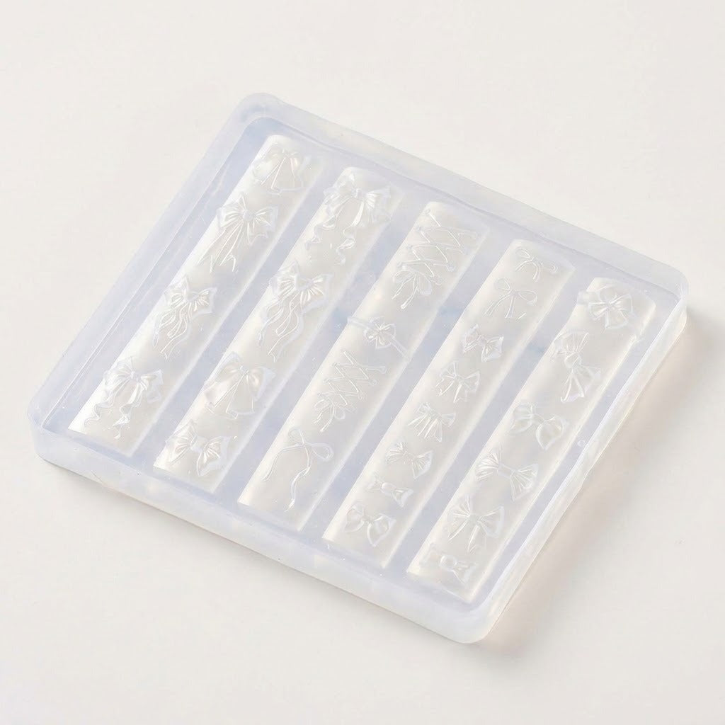 A translucent plastic rectangular mold with five vertical compartments, each containing an embossed floral and bow pattern, shown on a plain light background.