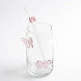 Clear glass tumbler with pink butterfly decorations and a clear straw featuring a pink butterfly accent, shown on a white background.