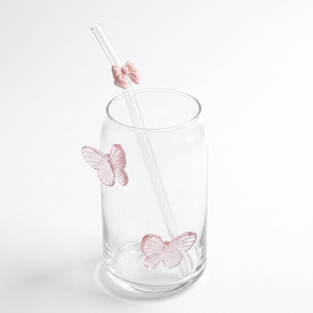 Clear glass tumbler with pink butterfly decorations and a clear straw featuring a pink butterfly accent, shown on a white background.