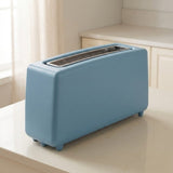 A light blue retro-style two-slot toaster sits on a cream-colored kitchen countertop with a softly blurred kitchen background.