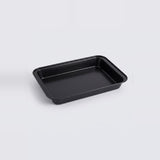 A rectangular black baking pan with raised edges, photographed on a clean light gray studio background.