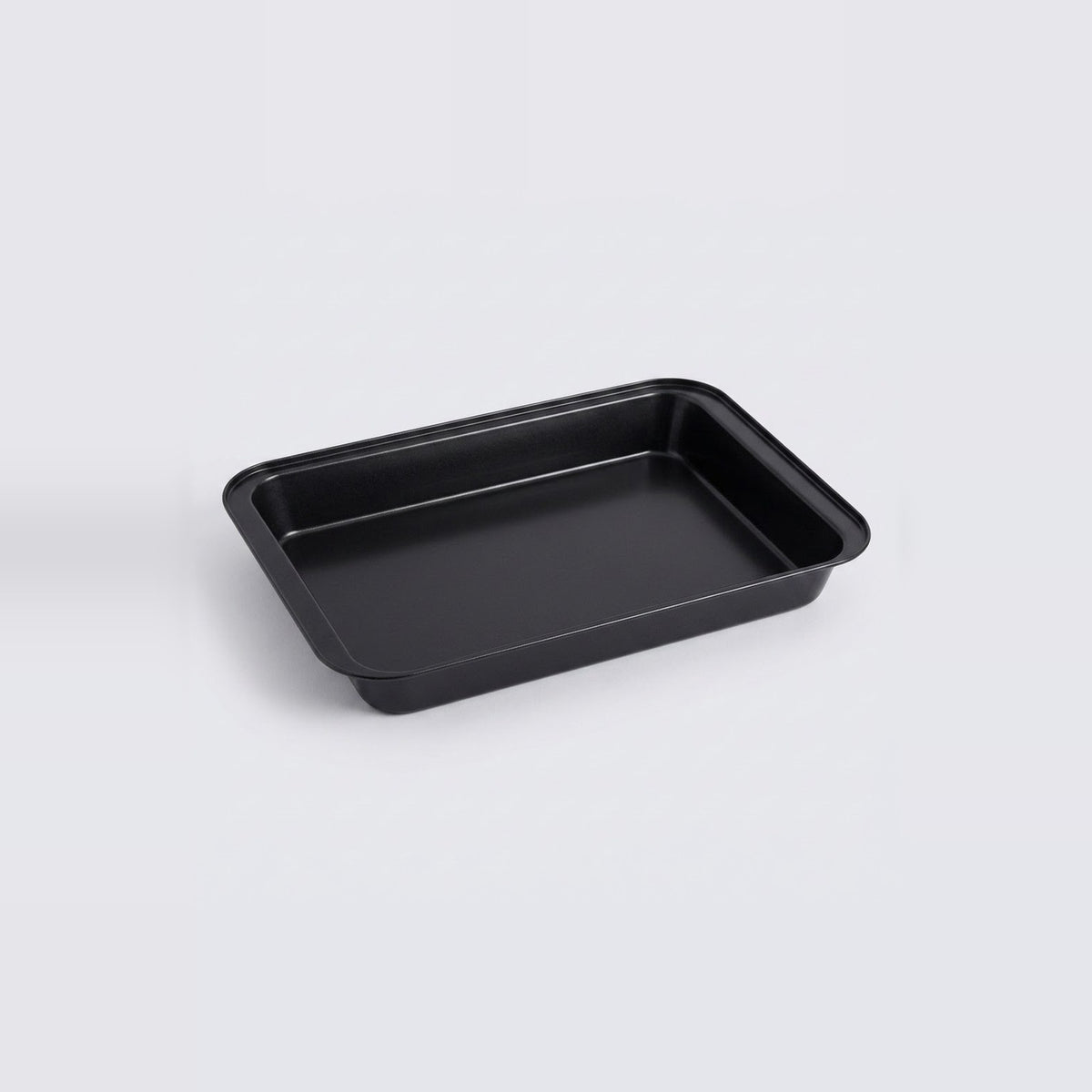 A rectangular black baking pan with raised edges, photographed on a clean light gray studio background.