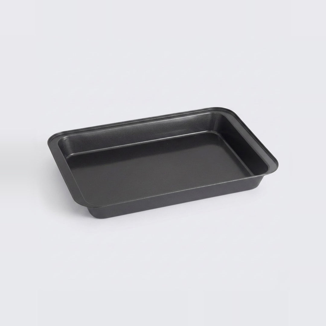 A rectangular black baking pan with raised edges, photographed on a clean light gray background.