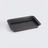 A rectangular black baking pan with raised edges, photographed on a clean light gray background.