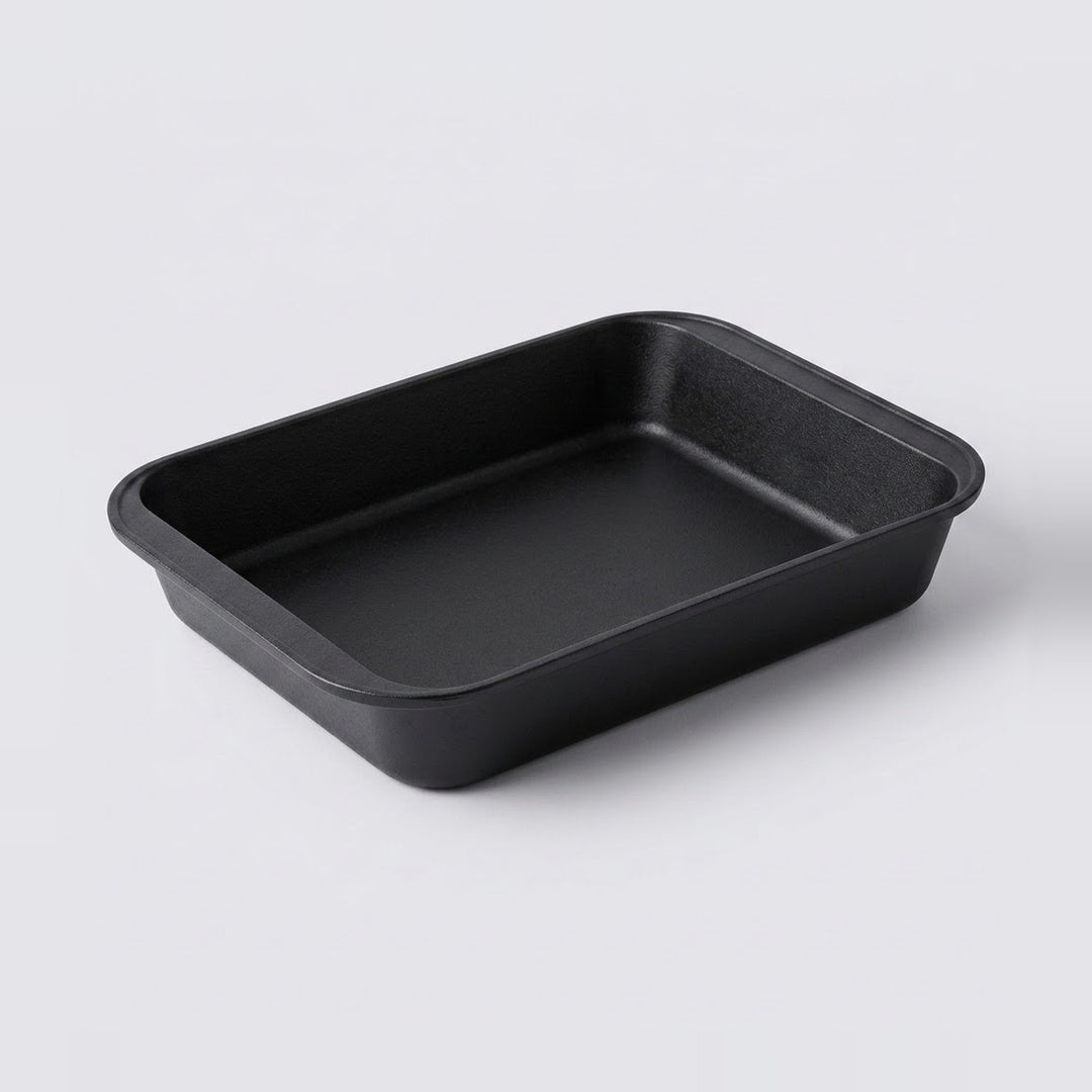 A rectangular black non-stick baking pan with rounded corners, shown from a three-quarters perspective on a light gray background.