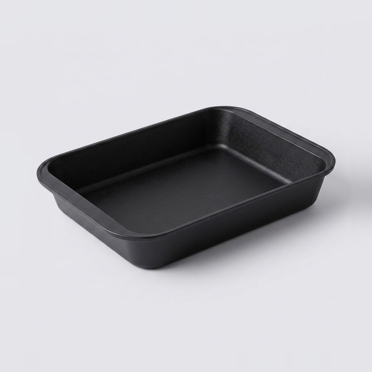 A rectangular black non-stick baking pan with rounded corners, shown from a three-quarters perspective on a light gray background.