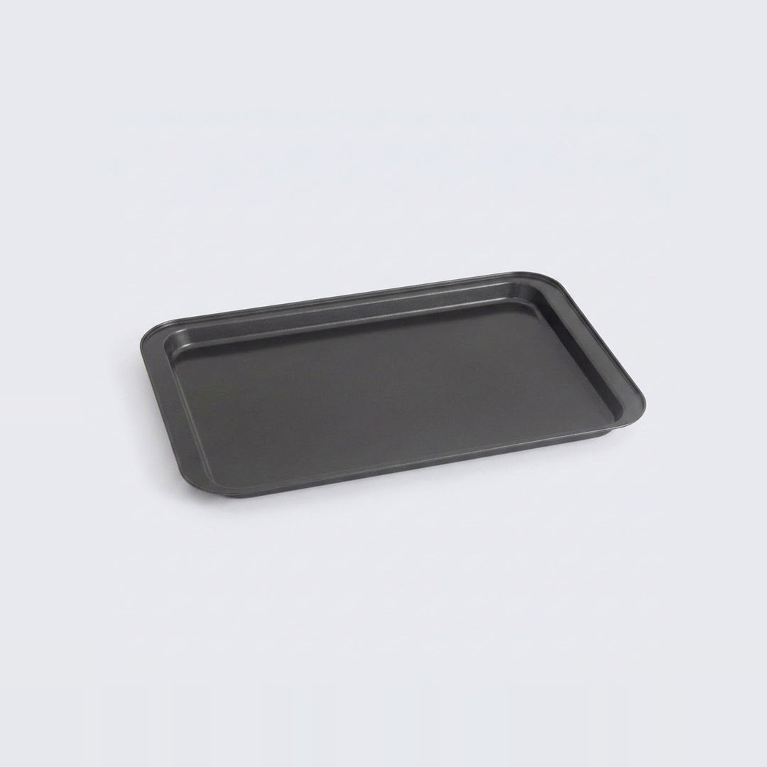 A rectangular black baking tray with raised edges, photographed at an angle on a light gray background.