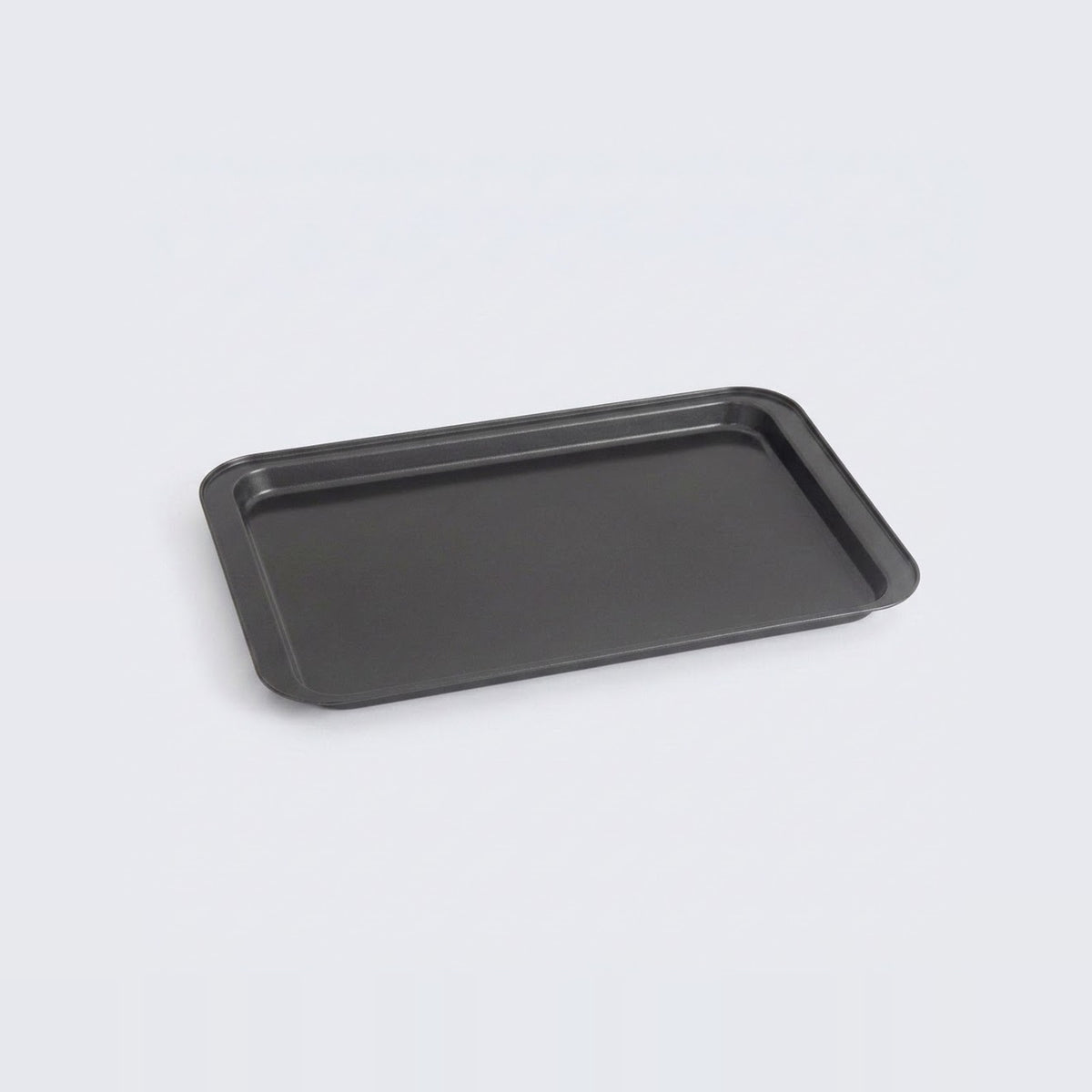 A rectangular black baking tray with raised edges, photographed at an angle on a light gray background.