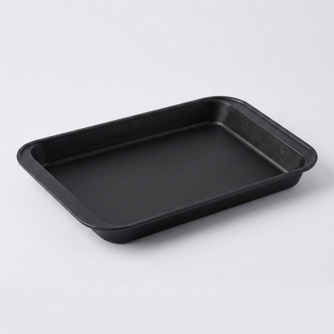 A rectangular black non-stick baking pan with raised rimmed edges, photographed on a clean light gray studio background.
