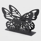 A black butterfly-shaped bookend with intricate cutout wing patterns and a flat rectangular base, photographed on a light gray background.