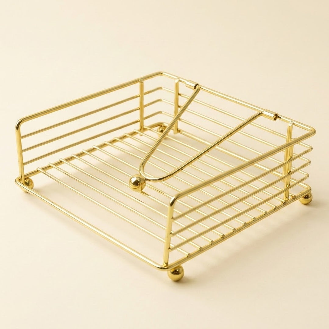 A gold-finished metal wire organizer tray with a slatted base and curved top bars, shown on a plain warm beige background.