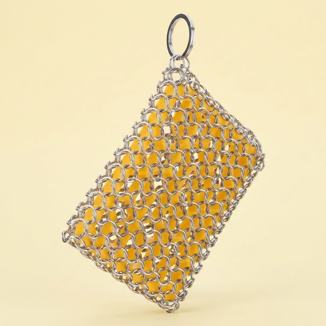 A rectangular metal mesh bag or pouch with a silver chainmail-style weave and a hanging ring at the top, shown against a plain warm beige background.