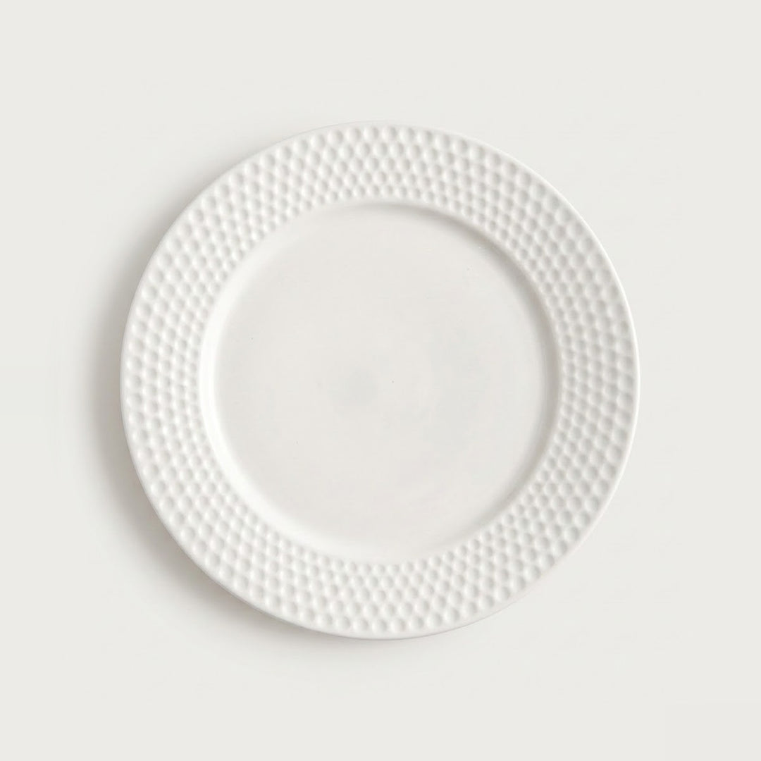 A white ceramic plate with a textured, dimpled border, shown from a top-down view against a light gray background.
