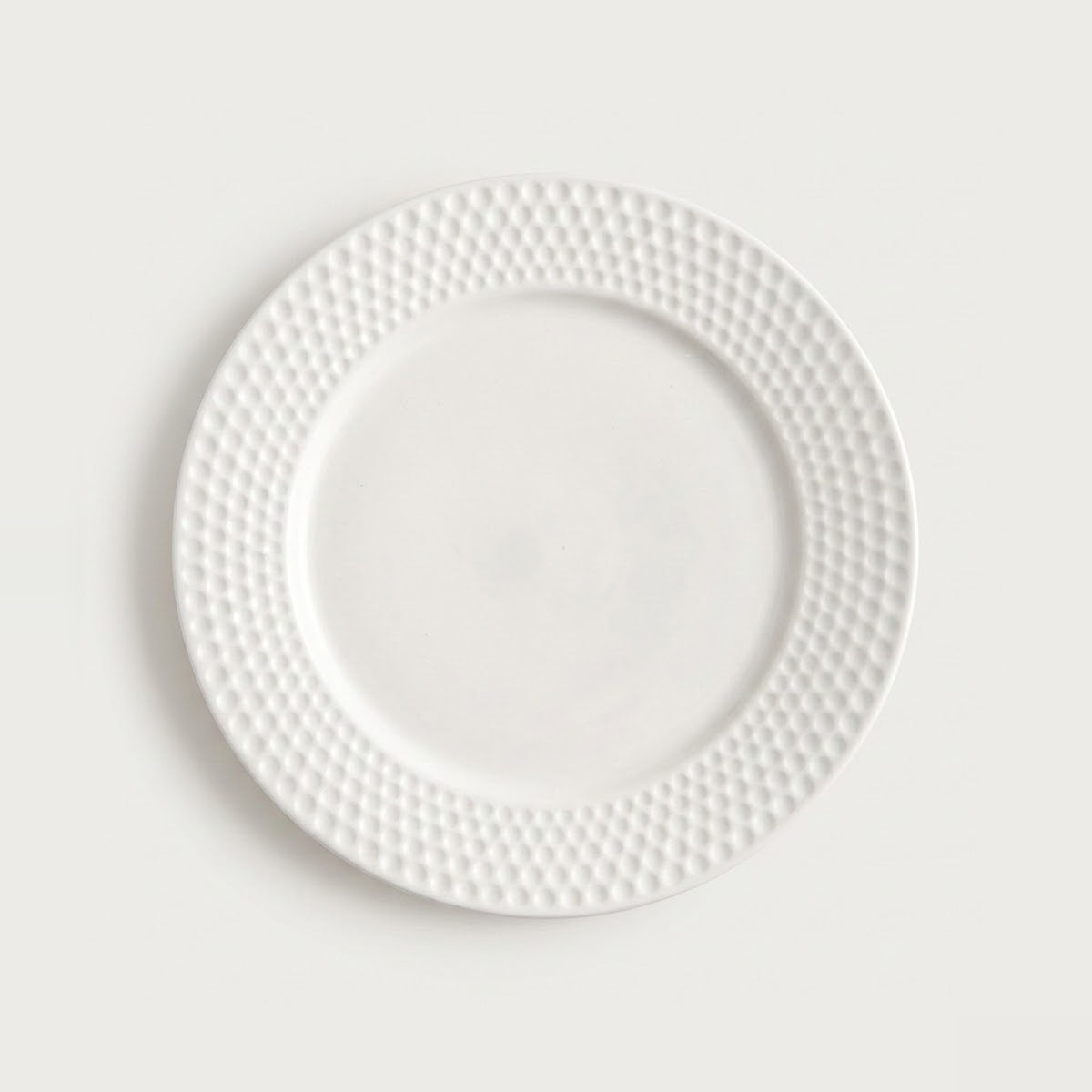 A white ceramic plate with a textured, dimpled border, shown from a top-down view against a light gray background.