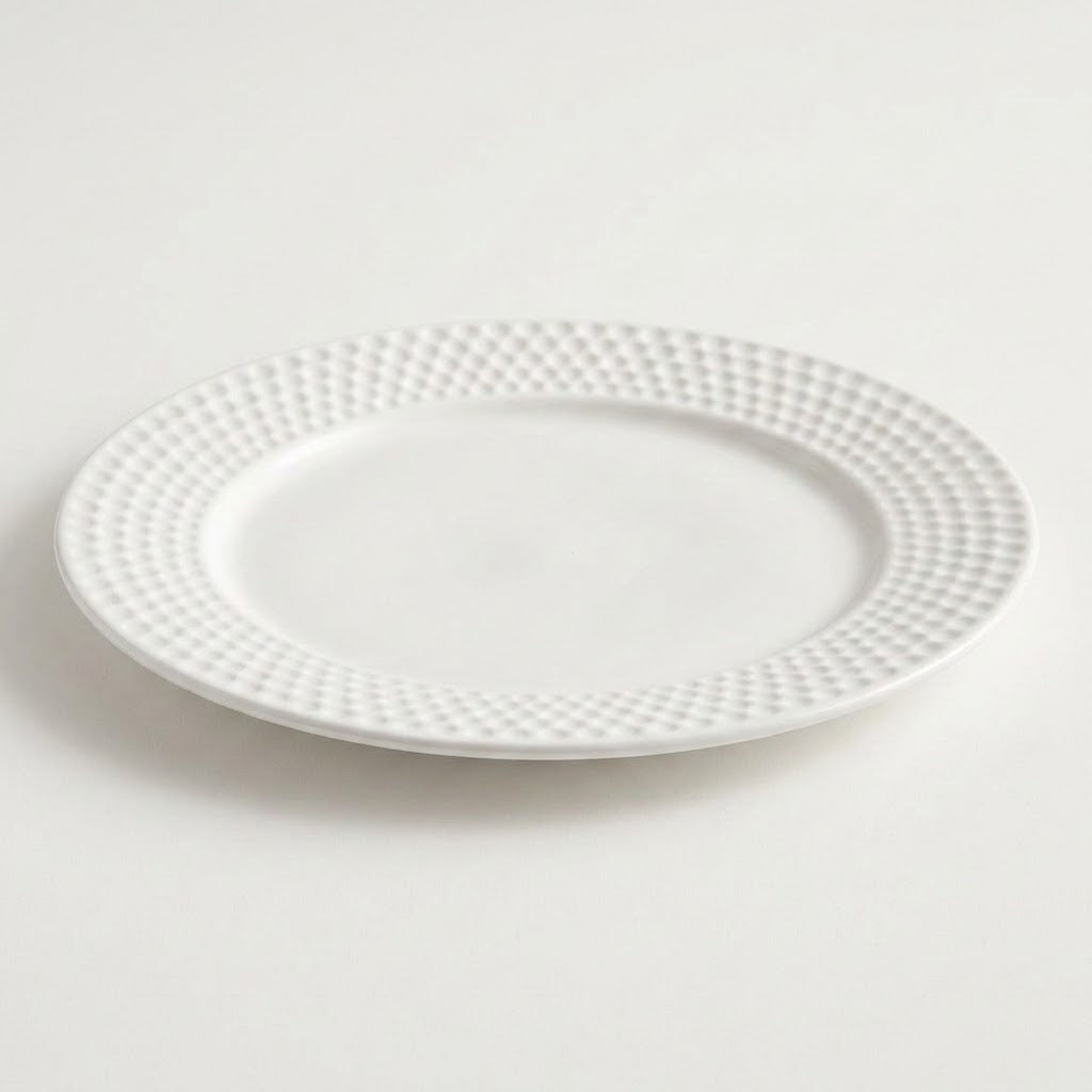 A white ceramic plate with a textured, dimpled pattern around the rim, shown on a clean white background.