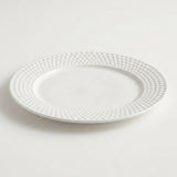 A white ceramic plate with a textured, dimpled pattern around the rim, shown on a clean white background.