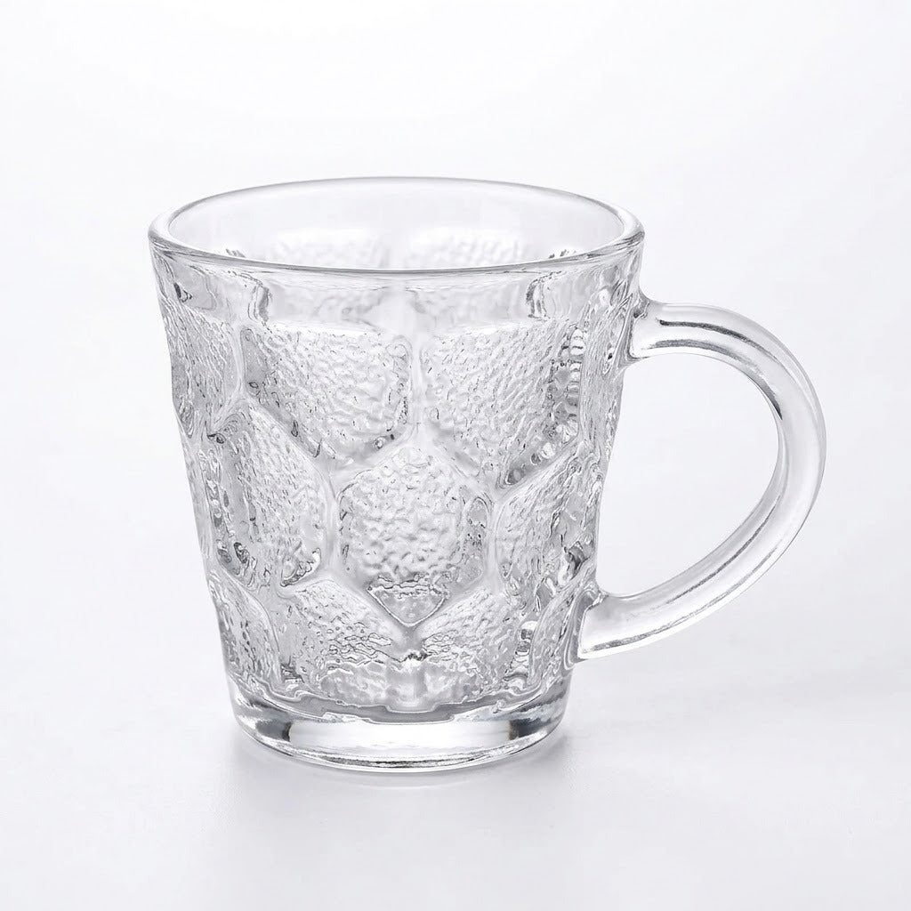 A clear glass mug with a textured, embossed honeycomb pattern and a curved handle, shown on a plain white background.