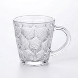 A clear glass mug with a textured, embossed honeycomb pattern and a curved handle, shown on a plain white background.