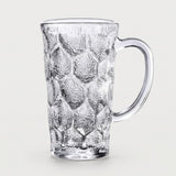 A clear textured glass mug with a honeycomb pattern and a curved handle, shown on a light gray background.