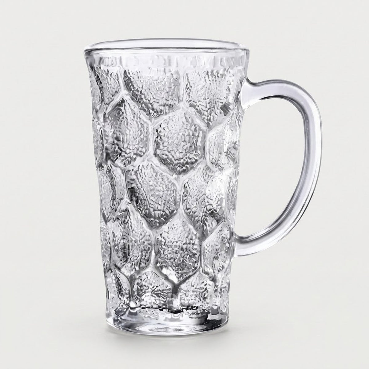 A clear textured glass mug with a honeycomb pattern and a curved handle, shown on a light gray background.