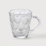 A clear textured glass mug with a honeycomb pattern and a curved handle, shown on a light gray background.
