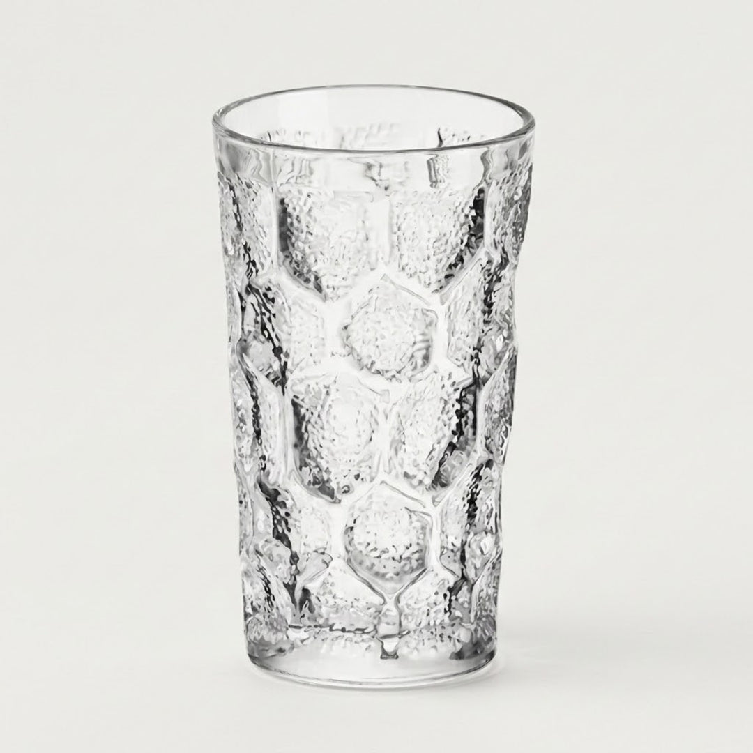 A clear textured glass tumbler with a honeycomb pattern, shown on a plain light gray background.