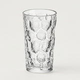 A clear textured glass tumbler with a honeycomb pattern, shown on a plain light gray background.