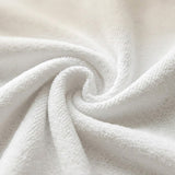 A close-up of white textured fabric arranged in a spiral swirl, showing the soft terry or looped material detail.