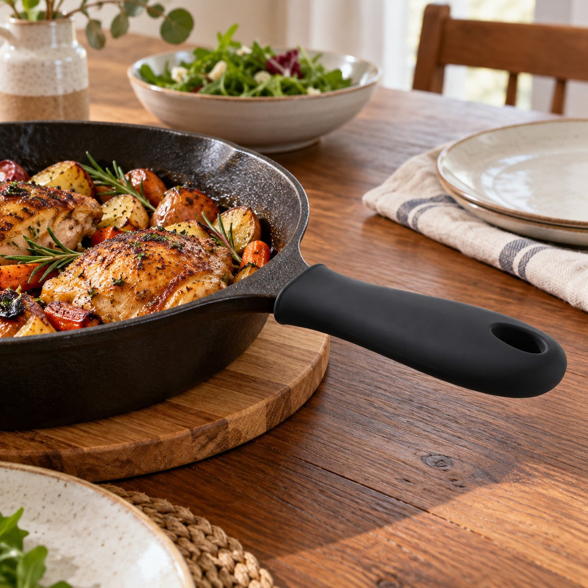 Black silicone pot handle cover protects a cast iron skillet handle on a dining table.