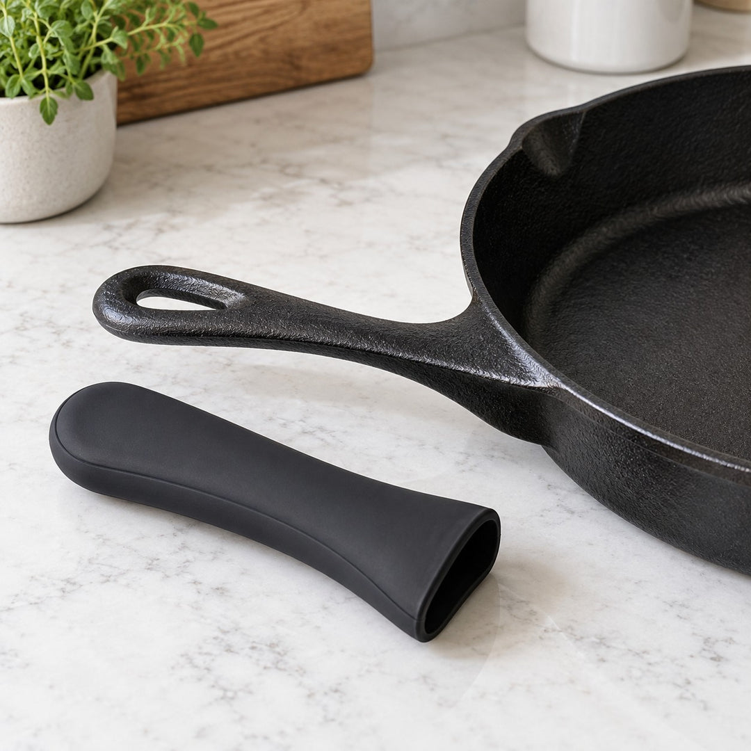 Black silicone pot handle cover shown beside a cast iron skillet handle for scale.