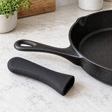 Black silicone pot handle cover shown beside a cast iron skillet handle for scale.
