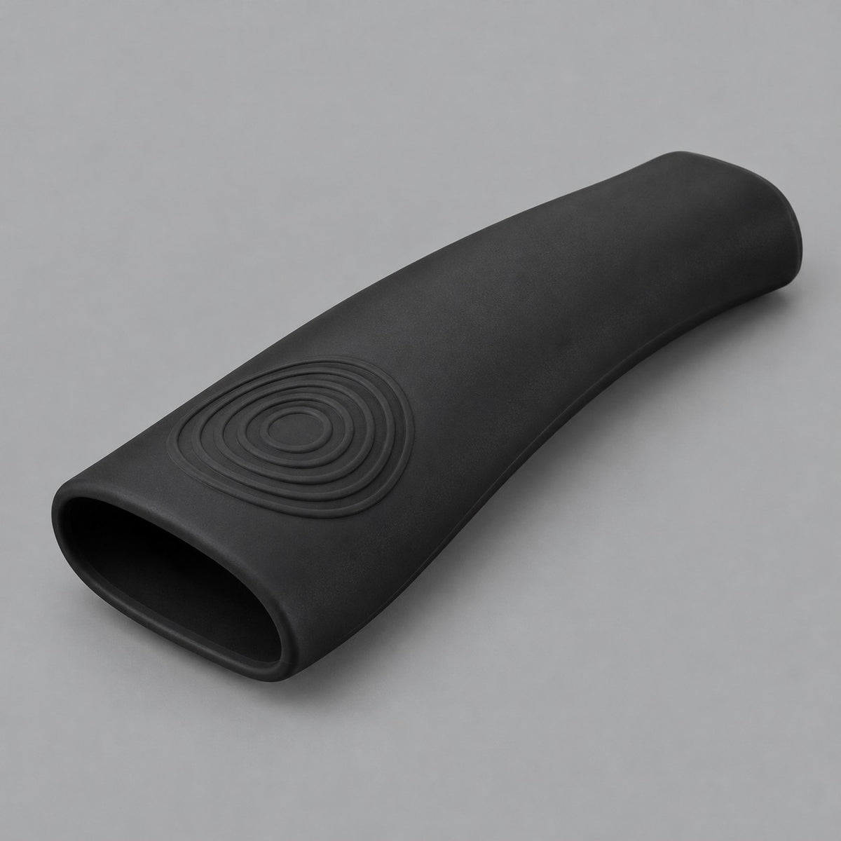 Single black silicone pot handle cover centered on a soft gray studio background.