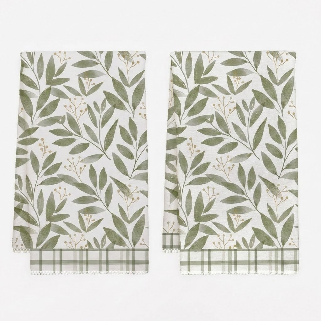 Two white kitchen towels with a green leaf pattern and green plaid borders, displayed side-by-side on a white background.