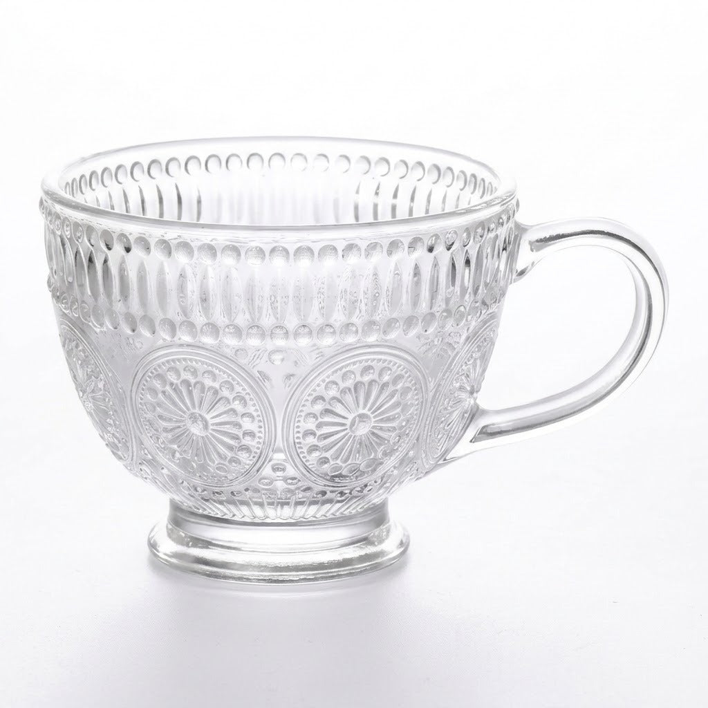 A clear glass teacup with embossed floral and vertical ribbed patterns, set against a plain white background.