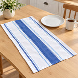 Blue striped cotton tea towel is laid beside a dinner plate and mug to show its table scale.