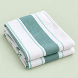 Green striped cotton tea towel folded on a soft green studio background.