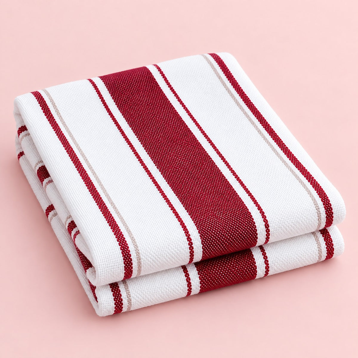Red striped cotton tea towel folded on a pale blush studio background.