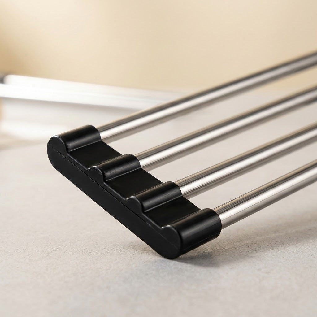 Close-up of a metal drying rack with four parallel silver rods and black plastic end caps on a light gray surface.