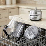 Cuisinart countertop blender base with two clear plastic pitcher and lid components resting in a dishwasher, set in a kitchen environment.