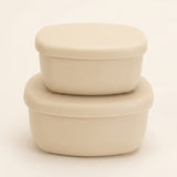 Two stacked oval plastic storage containers with matching lids in a warm cream or off-white color, set against a plain light background.