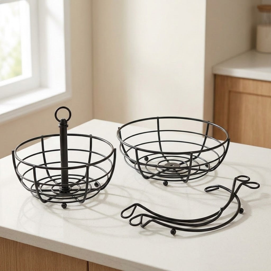 Two black metal wire fruit baskets on a white countertop in a kitchen setting, with a third matching wire accessory placed in front.