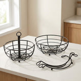 Two black metal wire fruit baskets on a white countertop in a kitchen setting, with a third matching wire accessory placed in front.