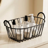 A black wire basket organizer with two handles sits on a light marble countertop, holding several clear bottles and white jars with blank labels.