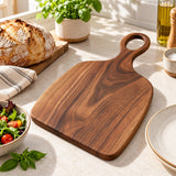 Handmade Acacia Cutting Board beside a dinner plate and bread to show its everyday kitchen scale.