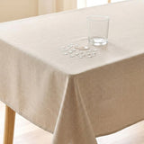 A beige tablecloth draped over a table, with a clear glass tumbler and a small water droplet spill on top to demonstrate water resistance.