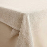 A close-up of a light beige linen tablecloth draped over the corner of a table, showing its textured woven fabric.