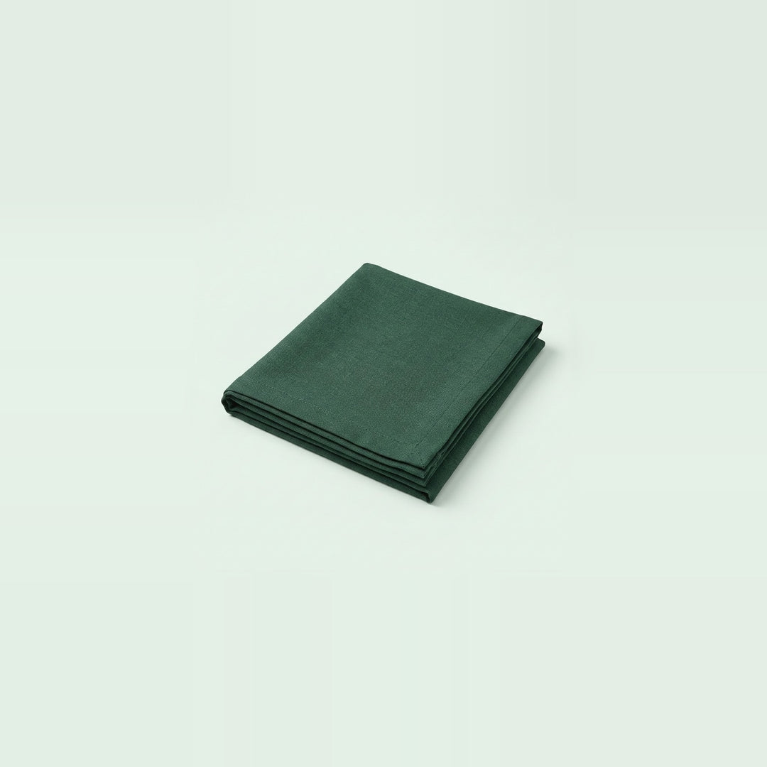 A folded dark green cloth napkin or pocket square, shown on a clean, solid, very light off-white background.