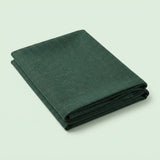 A folded dark green fabric item, likely a blanket, throw, or sheet, shown on a plain light green background.
